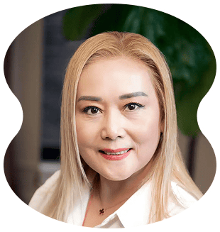 A woman with straight, blonde hair styled at Evertrue Salon and a white shirt smiles at the camera against a blurred background.