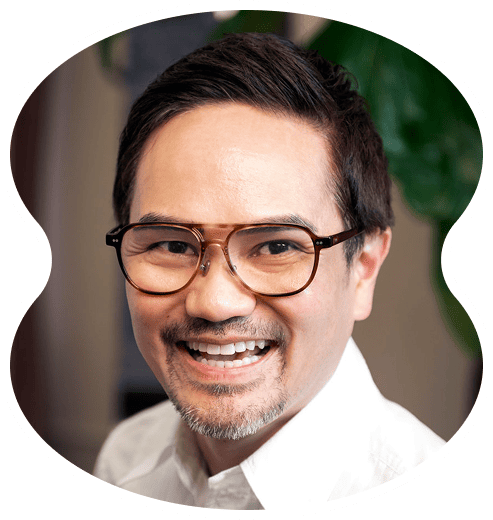 A man with short dark hair, glasses, and a goatee is smiling while wearing a white collared shirt—capturing the friendly spirit found at EverTrue Salon.